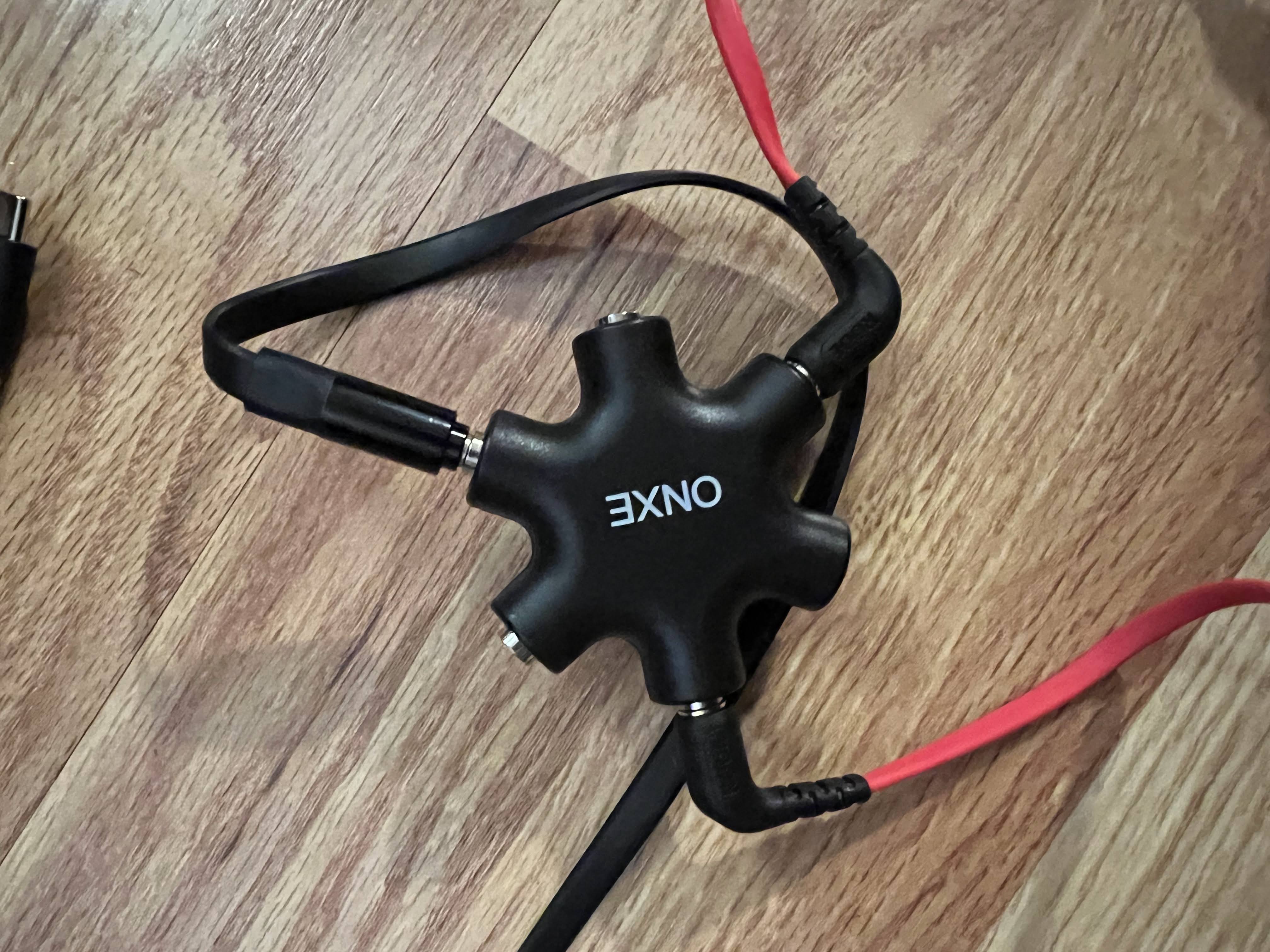 A headphone splitter with three audio cables plugged into it.